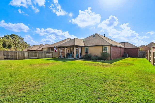 rear view of property featuring a yard and central AC