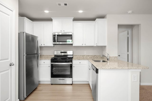 kitchen with white cabinetry, sink, light stone countertops, and appliances with stainless steel finishes