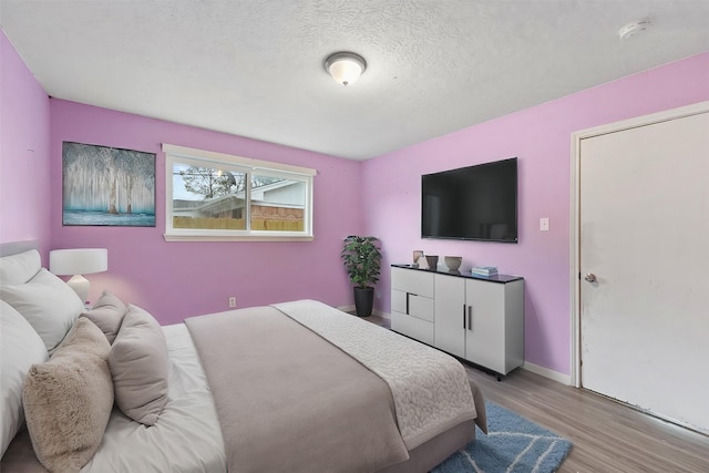 bedroom featuring a textured ceiling and light hardwood / wood-style flooring