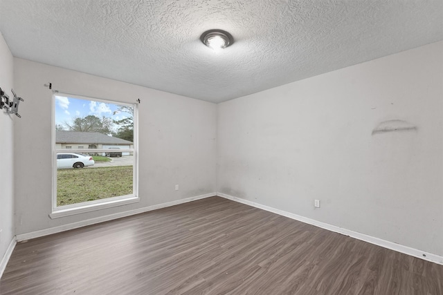 unfurnished room with dark hardwood / wood-style flooring, a textured ceiling, and a wealth of natural light