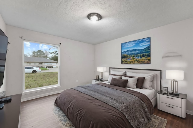 bedroom featuring dark hardwood / wood-style floors, a textured ceiling, and multiple windows