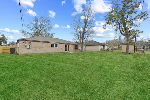 back of house with a yard and a storage shed