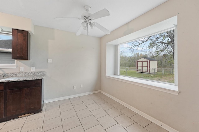 unfurnished dining area with light tile patterned flooring, a wealth of natural light, and ceiling fan