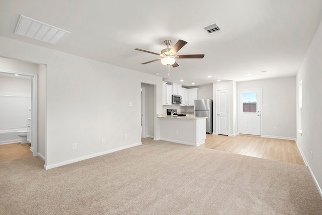 unfurnished living room featuring ceiling fan and light colored carpet