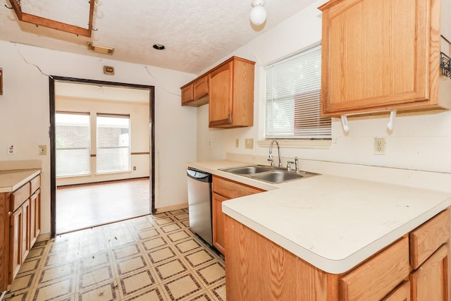 kitchen with a textured ceiling, stainless steel dishwasher, and sink