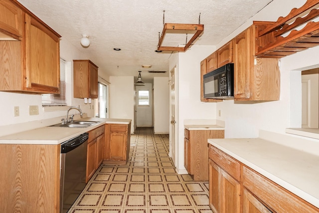 kitchen with decorative light fixtures, sink, stainless steel dishwasher, and a textured ceiling