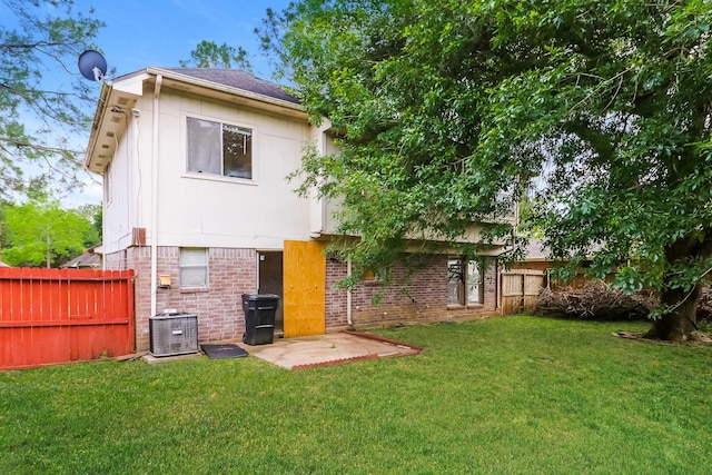 back of property with a lawn, a patio area, and central air condition unit