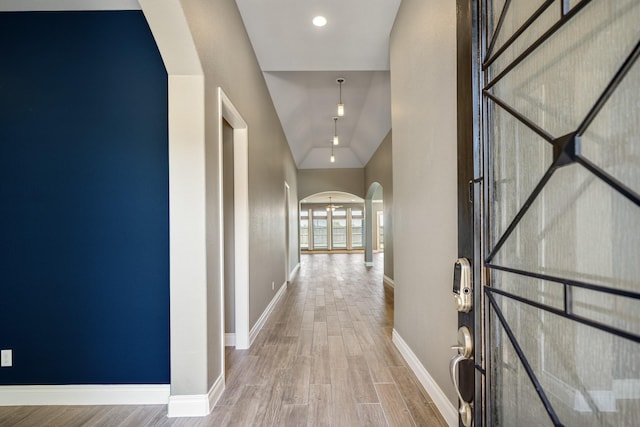 corridor with hardwood / wood-style flooring and lofted ceiling