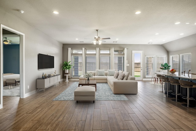 living room with a textured ceiling, vaulted ceiling, ceiling fan, and sink