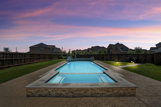 pool at dusk with a yard and an in ground hot tub