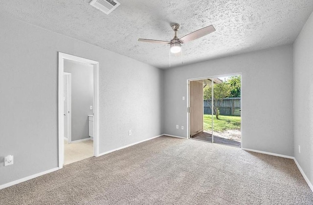 carpeted empty room featuring visible vents, a textured ceiling, baseboards, and a ceiling fan