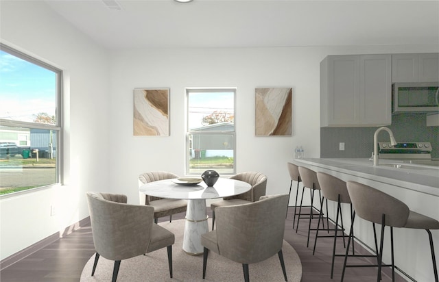 dining space featuring dark wood-type flooring and baseboards