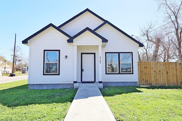 bungalow-style home with a front lawn and fence