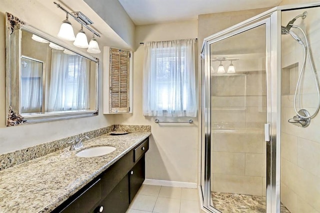 full bath with baseboards, a stall shower, vanity, and tile patterned floors