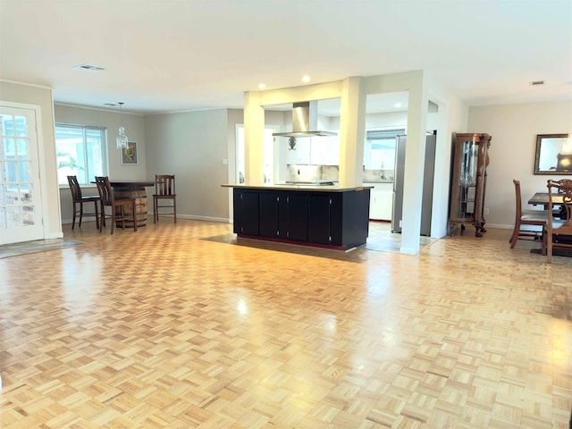 kitchen with a center island, baseboards, dark cabinetry, and exhaust hood