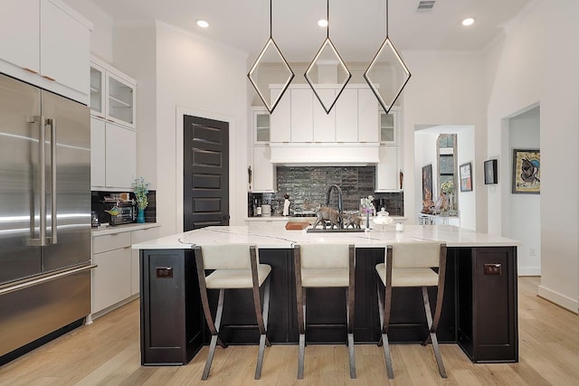 kitchen featuring pendant lighting, white cabinetry, stainless steel built in fridge, and a spacious island