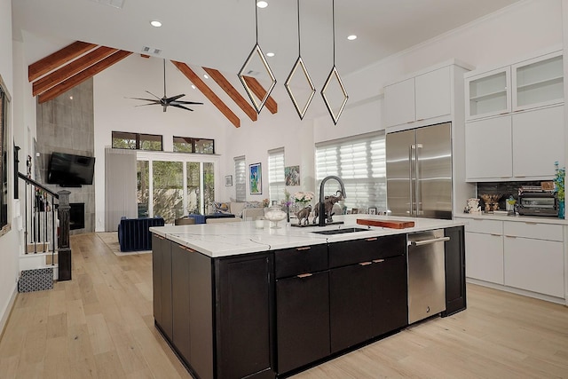 kitchen with sink, beamed ceiling, a center island with sink, white cabinets, and appliances with stainless steel finishes