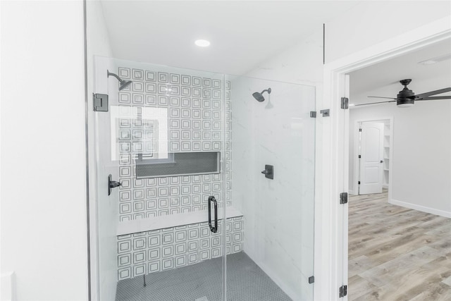 bathroom with ceiling fan, a shower with door, and wood-type flooring