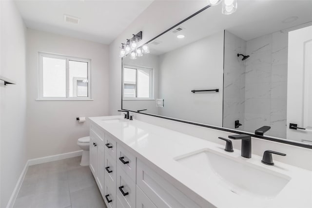 bathroom with vanity, toilet, and tiled shower