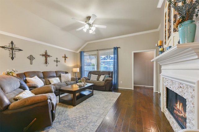 living room featuring a stone fireplace, crown molding, vaulted ceiling, ceiling fan, and dark hardwood / wood-style flooring