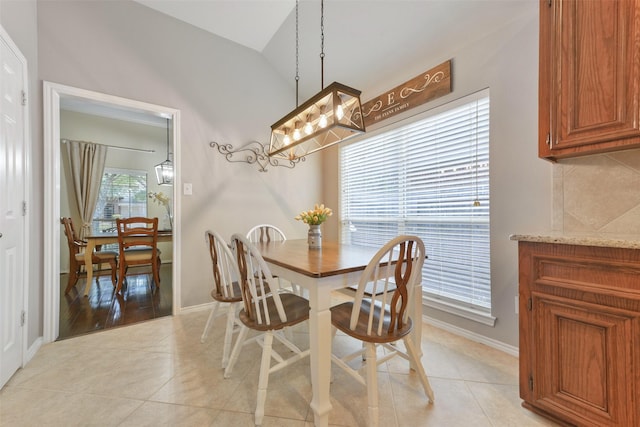 dining space with plenty of natural light, light tile patterned floors, and lofted ceiling