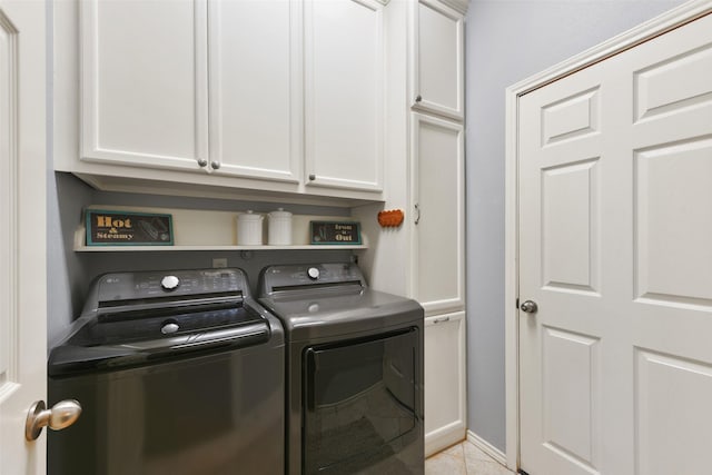 clothes washing area featuring cabinets, light tile patterned flooring, and washer and dryer