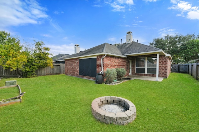 back of property with a lawn and an outdoor fire pit