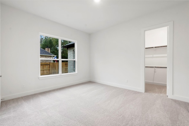 unfurnished bedroom with light carpet, a spacious closet, and a closet