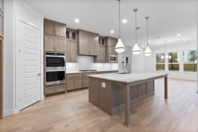 kitchen featuring backsplash, an island with sink, decorative light fixtures, a kitchen bar, and stainless steel appliances