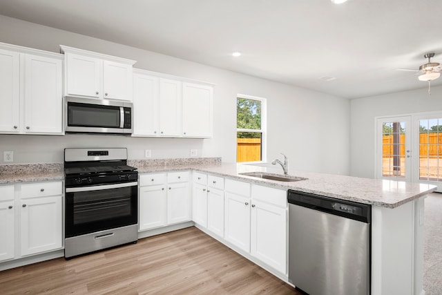 kitchen featuring kitchen peninsula, stainless steel appliances, sink, white cabinets, and light hardwood / wood-style floors