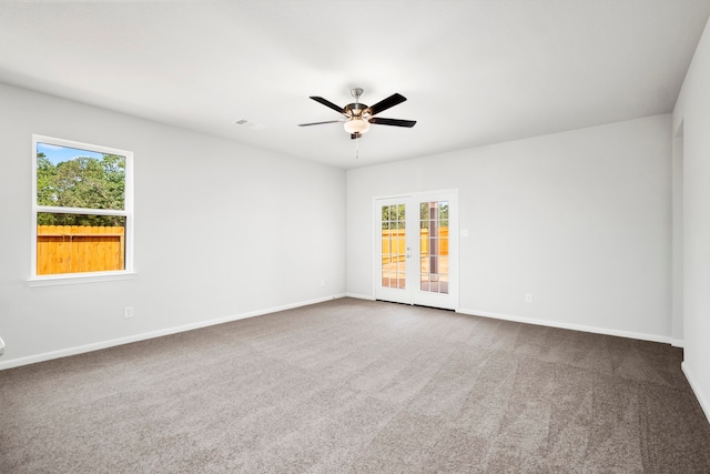 carpeted empty room with ceiling fan, plenty of natural light, and french doors