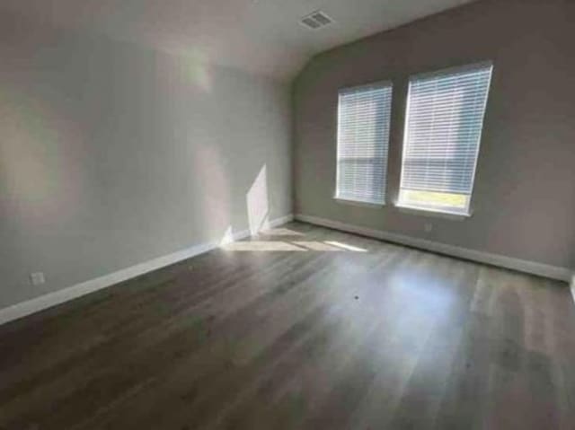 unfurnished room featuring dark hardwood / wood-style flooring and lofted ceiling