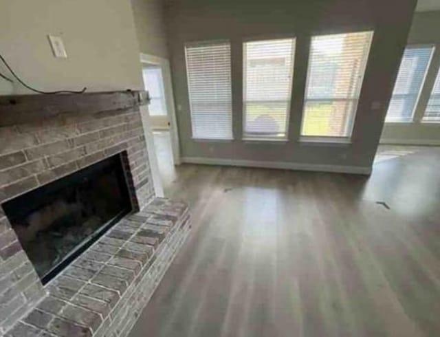 unfurnished living room featuring a fireplace, a healthy amount of sunlight, and wood-type flooring