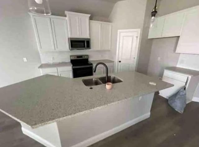 kitchen with white cabinets, appliances with stainless steel finishes, a center island with sink, and sink