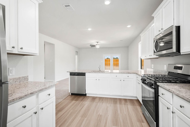 kitchen with kitchen peninsula, appliances with stainless steel finishes, ceiling fan, sink, and white cabinets