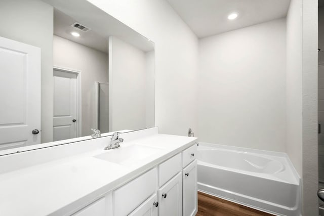 bathroom featuring a tub to relax in, vanity, and wood-type flooring