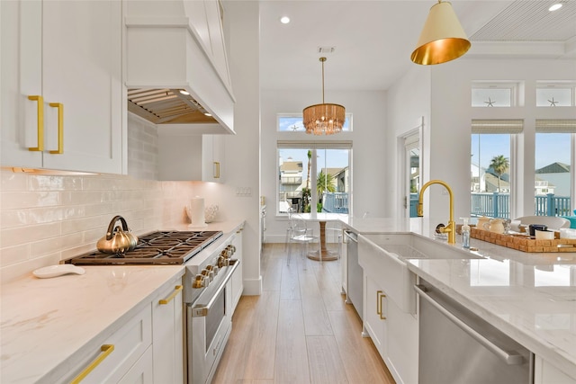 kitchen featuring premium range hood, appliances with stainless steel finishes, white cabinets, and hanging light fixtures