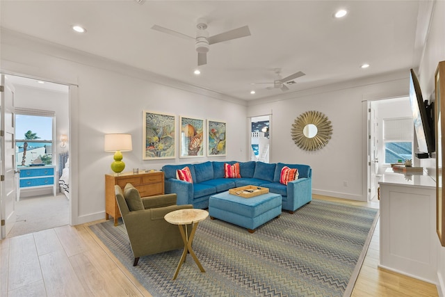 living room featuring light wood-type flooring, crown molding, and a healthy amount of sunlight