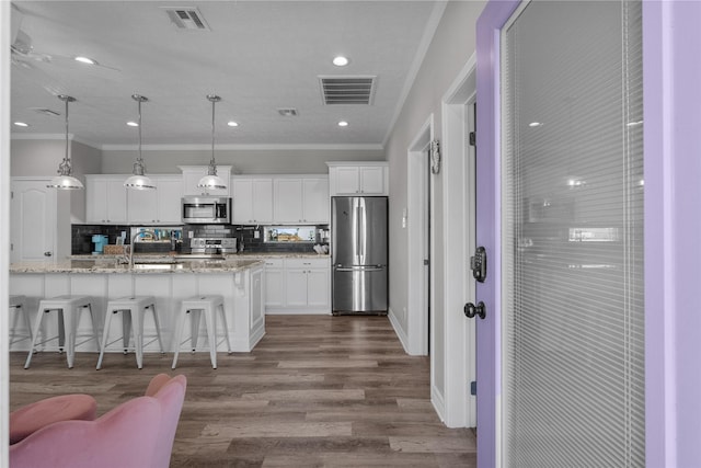 kitchen with white cabinetry, light stone countertops, hanging light fixtures, stainless steel appliances, and backsplash