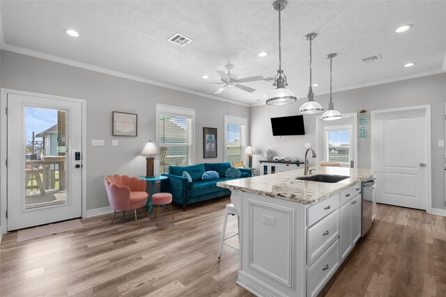 kitchen featuring light wood-type flooring, sink, a center island with sink, dishwasher, and white cabinets