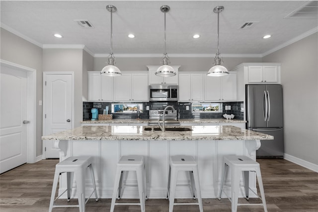 kitchen with white cabinetry, stainless steel appliances, and an island with sink