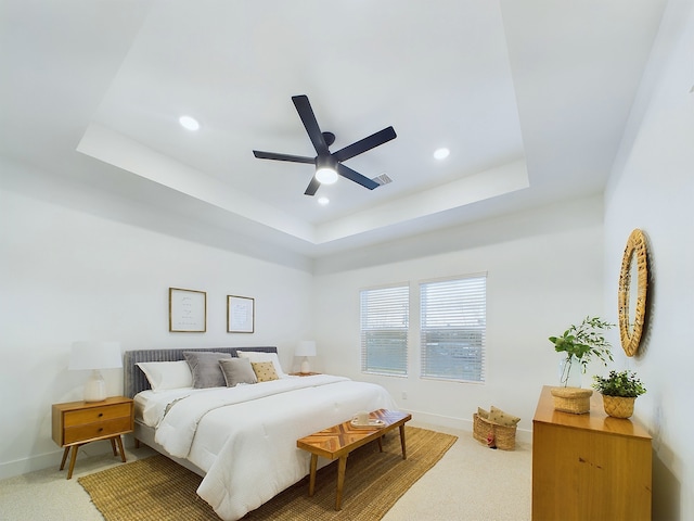 bedroom with carpet, a raised ceiling, and ceiling fan