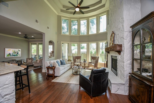 living room featuring a high ceiling, ornamental molding, and a stone fireplace