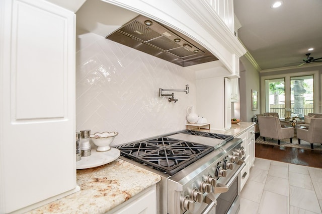 kitchen with white cabinetry, stainless steel range, light stone countertops, and custom range hood