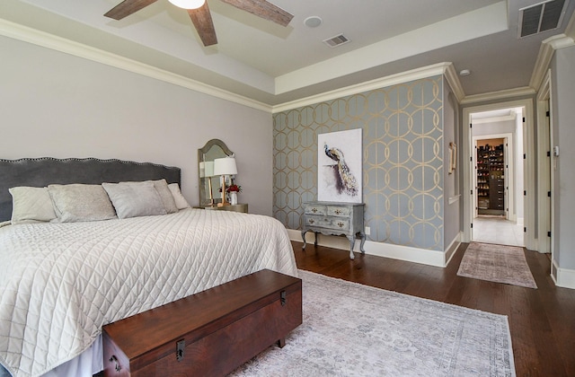 bedroom featuring hardwood / wood-style flooring, ornamental molding, ceiling fan, and a tray ceiling