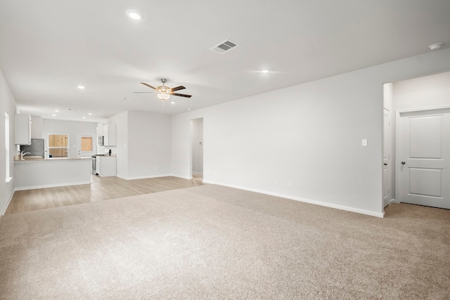 unfurnished living room featuring ceiling fan and light carpet