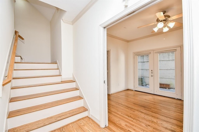 stairs featuring french doors, hardwood / wood-style flooring, ceiling fan, and crown molding