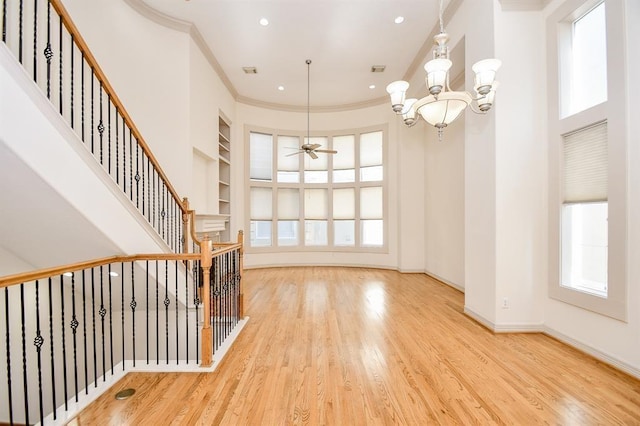 entryway with crown molding, ceiling fan with notable chandelier, and light wood-type flooring