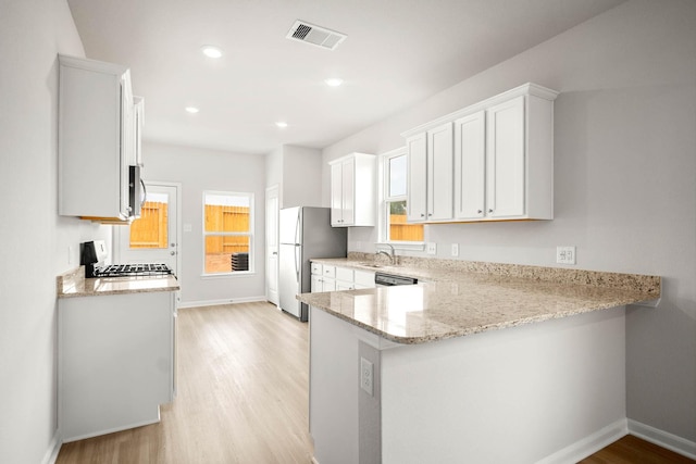 kitchen with white cabinets, appliances with stainless steel finishes, light wood-type flooring, and kitchen peninsula