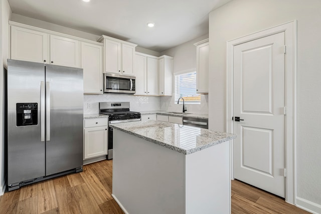 kitchen featuring white cabinets, light wood-type flooring, stainless steel appliances, and a kitchen island